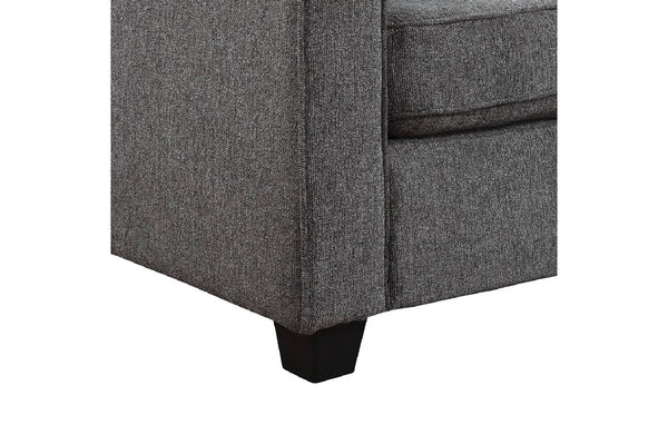 Primer plano de la esquina de un sillón o sofá tapizado en gris con patas de madera oscura, sobre un fondo blanco liso.