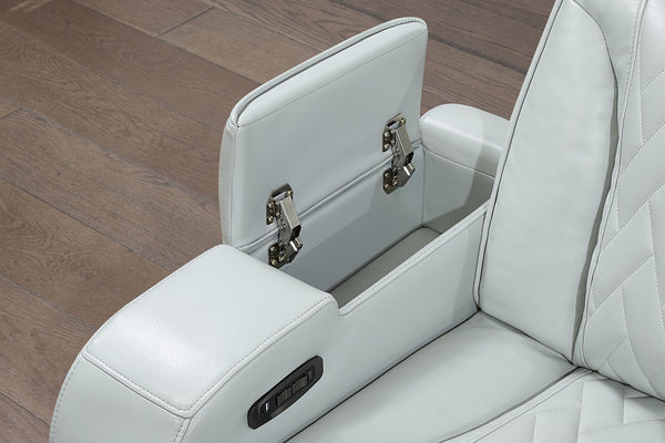 Primer plano de consola central integrada en sofá reclinable gris claro, con compartimento de almacenamiento abatible y controles eléctricos laterales. Tapizado acolchado con costuras decorativas para mayor funcionalidad y comodidad.