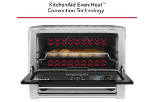 Horno de convección de sobremesa KitchenAid con puerta de cristal, mostrado con la puerta interior abierta y flechas rojas que indican el calor en la parte superior. El texto en la parte superior dice: «Tecnología de convección de calor uniforme KitchenAid».