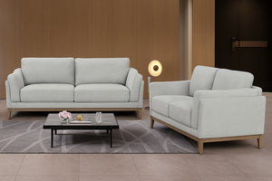Conjunto de sofá y loveseat gris claro en una moderna sala de estar con mesa de centro y elementos decorativos.