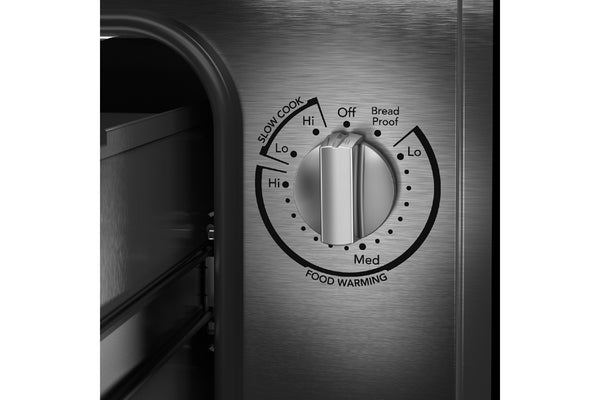 Primer plano del panel de control de un cajón calentador KitchenAid de 30 pulgadas en color verde, con perilla giratoria de acero inoxidable y opciones de calentamiento, cocción lenta y levado de pan visibles.