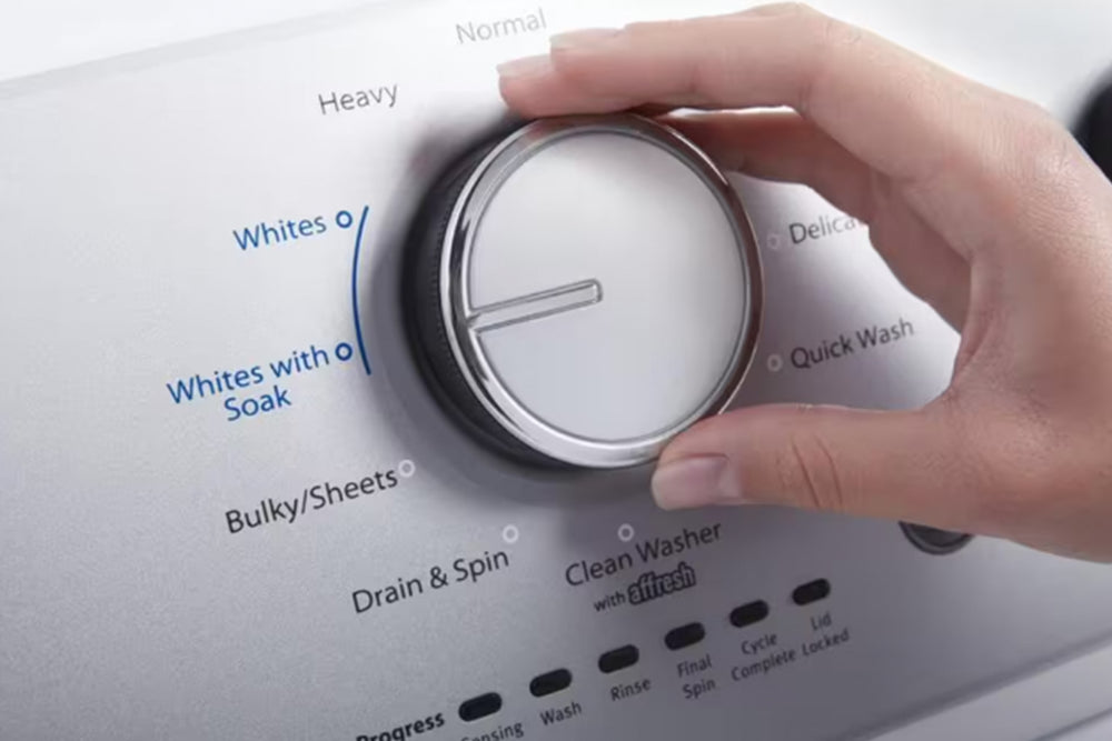 Lavadora blanca con panel de control plateado sobre fondo blanco.