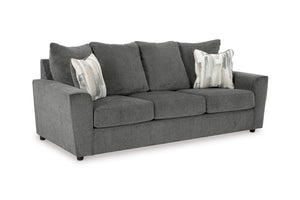 Sofá gris con cojines estampados sobre fondo blanco.