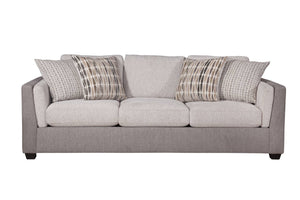 Vista frontal de sofá con acolchado crema y gris claro con cuatro cojines decorativos con patrones, todo sobre un fondo blanco. 