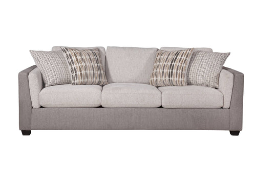 Vista frontal de sofá con acolchado crema y gris claro con cuatro cojines decorativos con patrones, todo sobre un fondo blanco. 