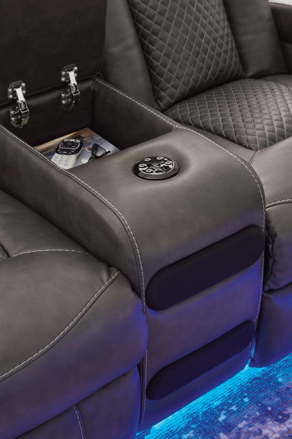 Asiento de reclinable gris con portavasos y panel de control, iluminado con luz azul.