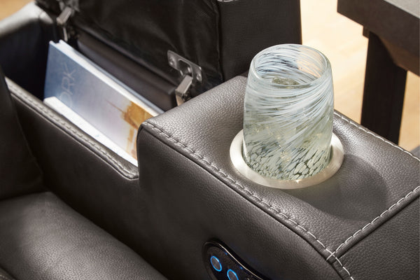 Un vaso de agua sobre un portavaso en el brazo del reclinable.