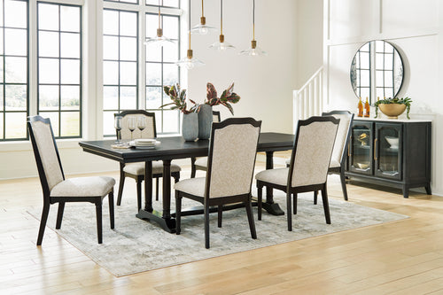 Comedor con mesa rectangular de madera oscura y seis sillas tapizadas en beige, respaldos altos y patas oscuras. Ambientado con aparador, espejo redondo, lámparas colgantes y grandes ventanales.