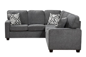 Sofá seccional de tela gris con chaise longue orientada hacia la derecha, con dos cojines decorativos estampados, que se muestra sobre un fondo blanco liso.