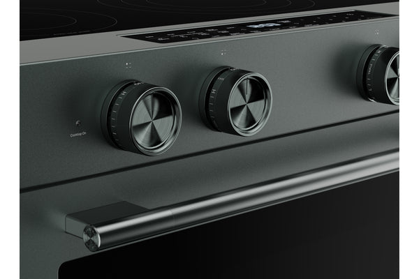 Primer plano del panel de control de un horno eléctrico moderno de color verde, con tres perillas metálicas redondas y una manija horizontal, sobre un fondo oscuro.