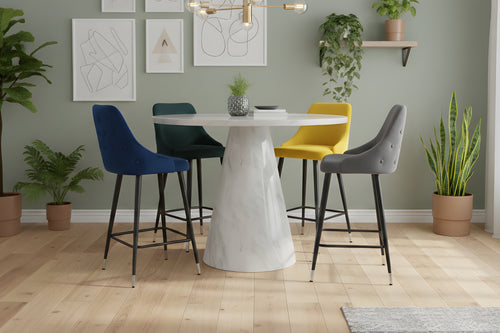 Mesa redonda con diseño de mármol blanco con cuatro sillas acolchados de colores distintos, con reposapiés y respaldar en una sala con plantas decorativas. 