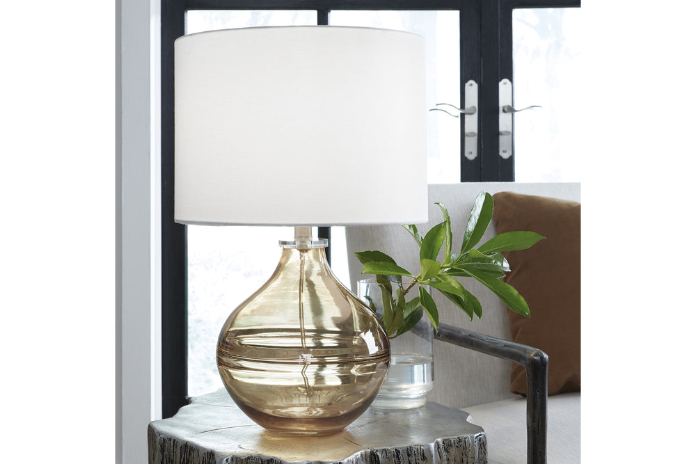 Lámpara de sobremesa con base de cristal marrón y pantalla blanca sobre fondo blanco.