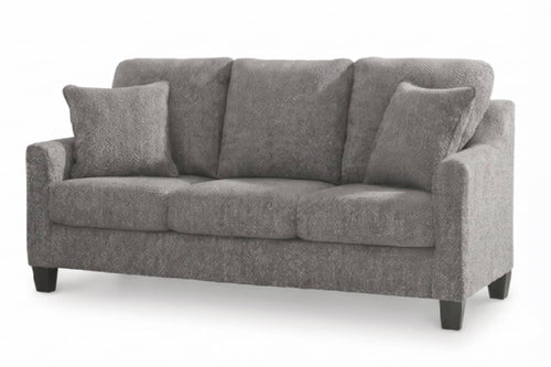 Un sofá de tres plazas tapizado en color gris, con cojines decorativos a juego y patas de madera oscura, mostrado sobre un fondo blanco liso.