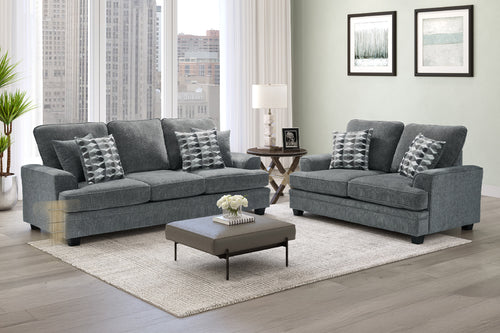 Sofá y loveseat de color gris con cojines decorativos y con mesa de centro en una sala moderna dentro de un apartamento. 