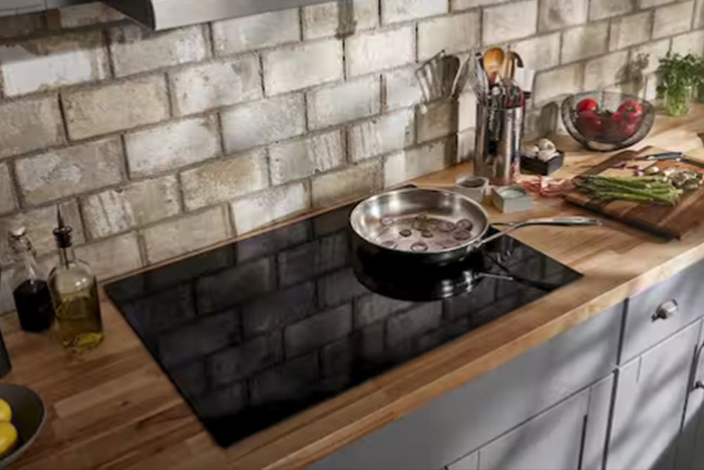 Cubierta de inducción KitchenAid empotrable con superficie de vidrio cerámico negro. Cuenta con cinco zonas de cocción circulares y controles táctiles digitales integrados en la parte frontal para un diseño moderno y minimalista.