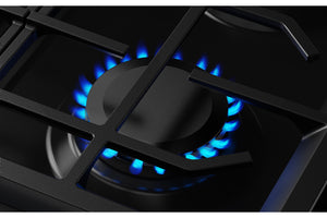 Primer plano de un quemador de estufa de gas negro con llamas azules encendidas bajo la rejilla.