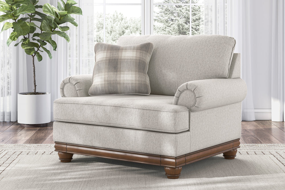 Silla de acento de color beige con brazos y un cojín decorativo sobre un fondo blanco. 