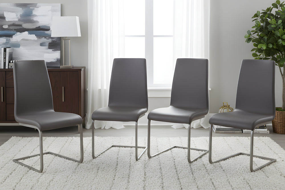 Cuatro sillas grises con patas metálicas en un salón moderno con una planta y una ventana al fondo.