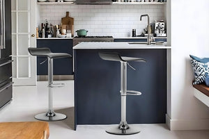 Dos taburetes de color negro en un fondo de cocina con elementos decorativos. 