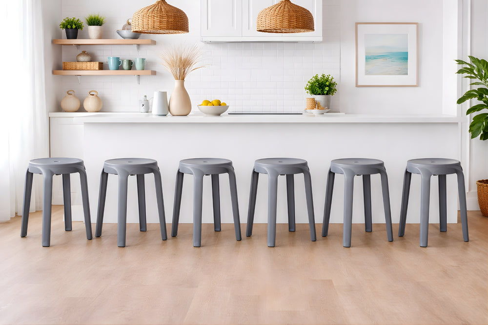 Fila de taburetes grises en una cocina moderna con armarios blancos y elementos decorativos.