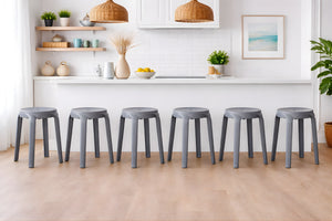 Fila de taburetes grises en una cocina moderna con armarios blancos y elementos decorativos.