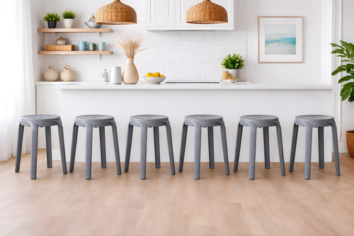 Fila de taburetes grises en una cocina moderna con armarios blancos y elementos decorativos.