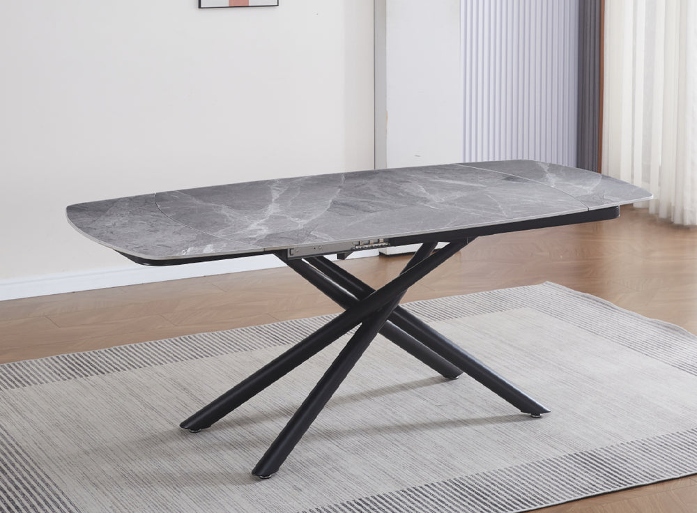 Mesa de comedor rectangular moderna con superficie gris y base metálica negra en forma de X, presentada sobre una alfombra con textura en un ambiente minimalista
