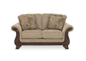 Loveseat beige con cojines decorativos sobre fondo blanco.