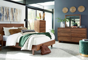 Dormitorio contemporáneo con cama de madera, mesa de noche, cómoda con espejo y cajonera alta a juego. La habitación incluye ropa de cama blanca, detalles decorativos en tonos verdes, arte mural y amplios ventanales que aportan luz natural.