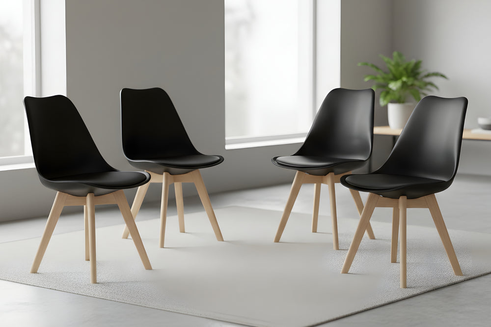 Cuatro sillas negras con patas de madera dispuestas en una habitación moderna.