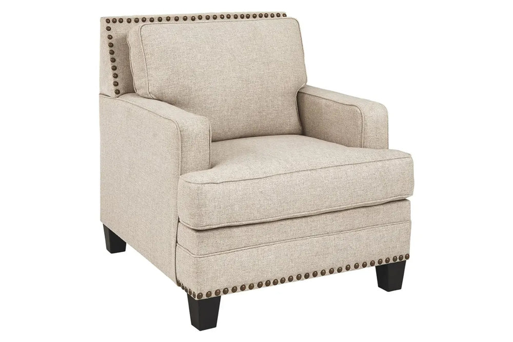 Sillón beige con ribete de tachuelas sobre fondo blanco.