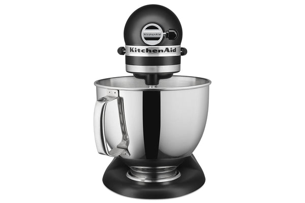 Una batidora KitchenAid con cabezal y base negros, y un gran bol de acero inoxidable con asa, mostrada sobre un fondo blanco liso.