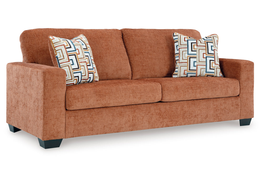 Sofá de color anaranjado con cojines sobre su fondo blanco. 