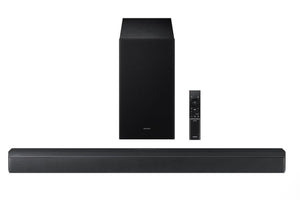 Barra de sonido negra con subwoofer y control remoto sobre fondo blanco. 