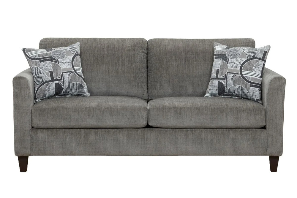 Sofá moderno tapizado en tela gris con cojines de asiento amplios, apoyabrazos rectos y dos cojines decorativos con diseño geométrico en tonos gris y blanco, presentado sobre fondo blanco.