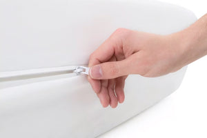 Mano sosteniendo una cremallera plateada sobre un fondo blanco.