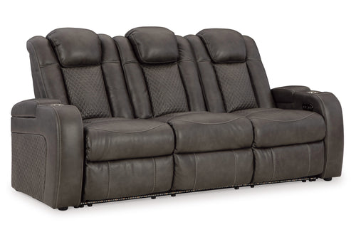 Sofá reclinable eléctrico con cabecera y reposapiés ajustables, integrado con luz LED, con portavasos y de color marrón oscuro, en un fondo blanco. 