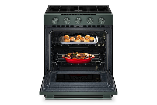 Una estufa de gas de color verde con la puerta del horno abierta, que deja ver una bandeja para hornear con panecillos en la rejilla superior y una cazuela roja en la rejilla inferior.