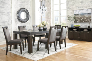 Un juego de comedor de 7 piezas que incluye una mesa rectangular de madera oscura y seis sillas a juego de respaldo alto con asientos tapizados en marrón, presentado en un ambiente de comedor moderno con un aparador y paredes de piedra.
