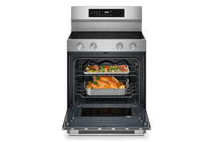 Horno independiente de acero inoxidable con la puerta abierta, que deja ver dos bandejas con pollo asado y verduras en su interior. El horno cuenta con un panel de control digital en la pared trasera y perillas plateadas en la parte frontal.
