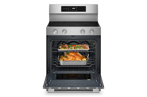 Horno independiente de acero inoxidable con la puerta abierta, que deja ver dos bandejas con pollo asado y verduras en su interior. El horno cuenta con un panel de control digital en la pared trasera y perillas plateadas en la parte frontal.