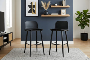 Dos taburetes negros en una sala de estar con una pared azul, estantes y una planta.