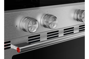 Primer plano del panel de control de un horno empotrado de acero inoxidable con tres perillas redondas plateadas, una manija horizontal con un detalle rojo y una placa de cocción de vidrio negro.
