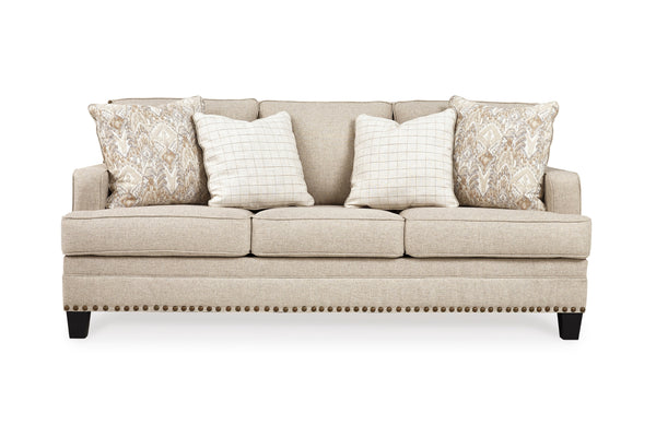 Sofá de color crema con cojines decorativos sobre un fondo blanco. 