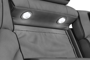 Primer plano del respaldo central de un sofá reclinable gris oscuro con dos luces LED de lectura integradas. Tapizado acolchado de textura suave y diseño ergonómico orientado al confort y entretenimiento en el hogar.