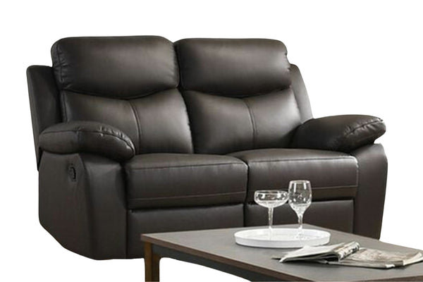 Loveseat reclinable de color negro con objetos decorativos sobre un fondo blanco. 