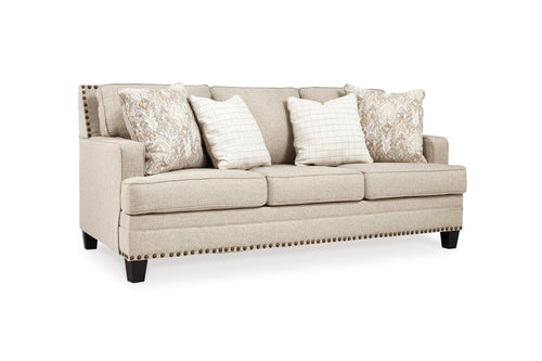 Sofá de color crema con cojines decorativos sobre un fondo blanco. 