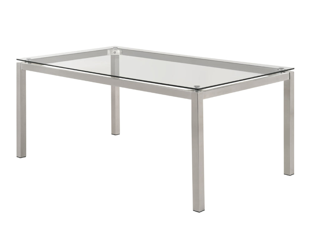Una mesa de comedor rectangular y moderna con tablero de vidrio transparente y patas finas de metal plateado, mostrada sobre un fondo blanco liso.