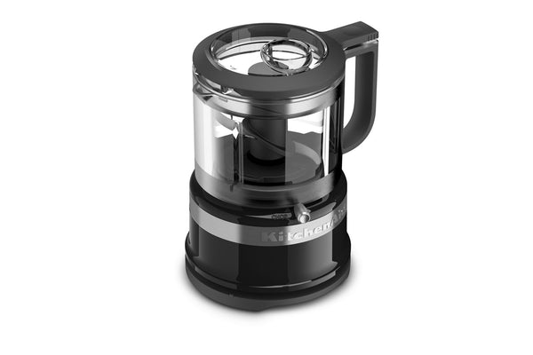 Un procesador de alimentos KitchenAid en color negro y transparente, con base, asa y tapa negras, recipiente transparente y detalles metálicos plateados.