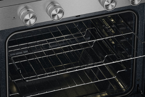 Primer plano del interior de un horno con dos rejillas metálicas dentro de una puerta de cristal oscuro, donde se aprecia parte de un panel de control de acero inoxidable y perillas plateadas en la parte superior.